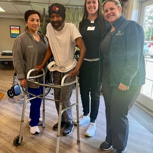 Man holding on to walker with three caregivers