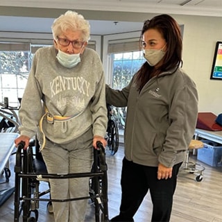 Woman with walker standing next to caregiver